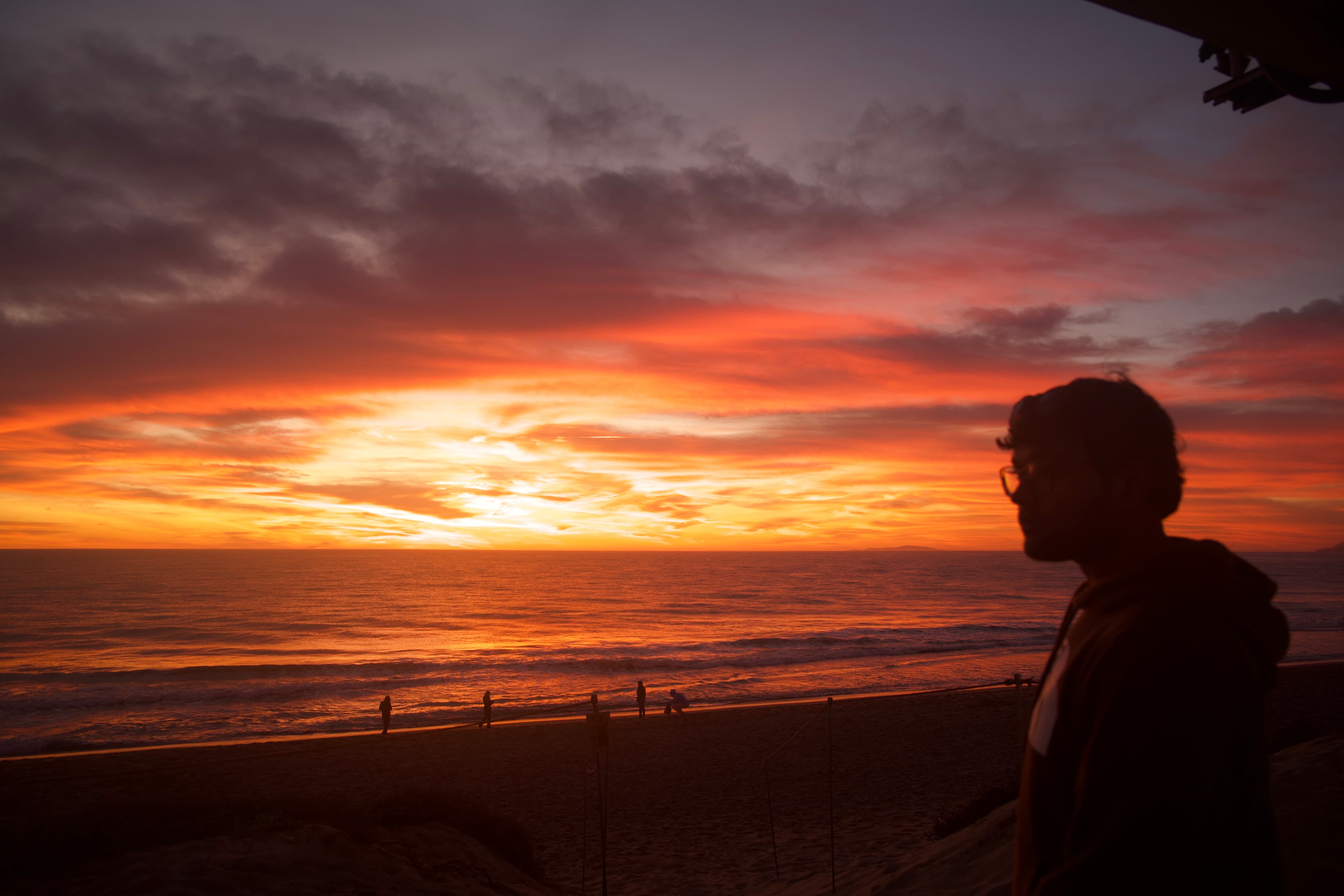 Aayush silhouetted against a vivid Pacific sunset