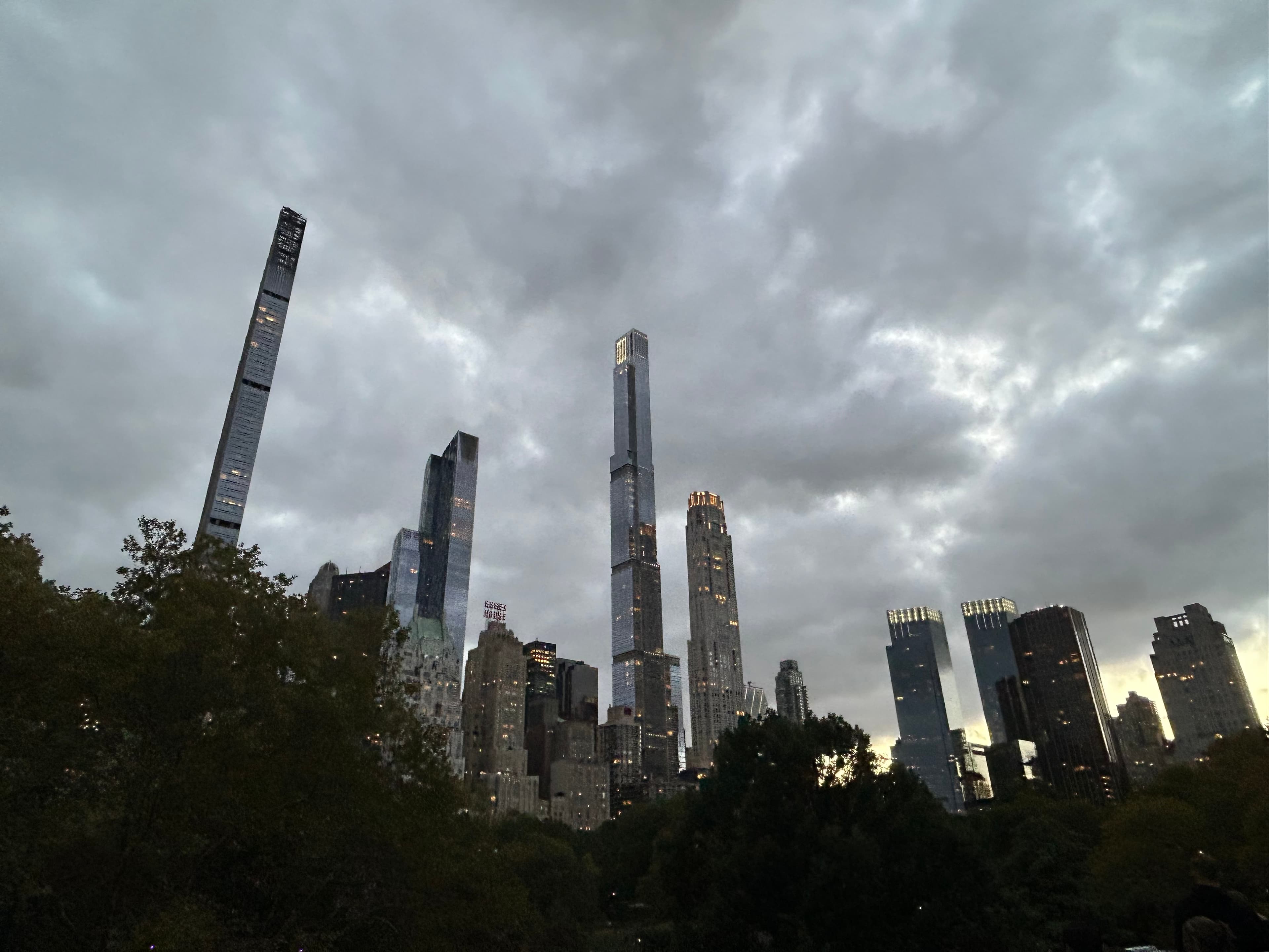 Midtown Manhattan supertalls piercing through a dramatic overcast sky from Central Park