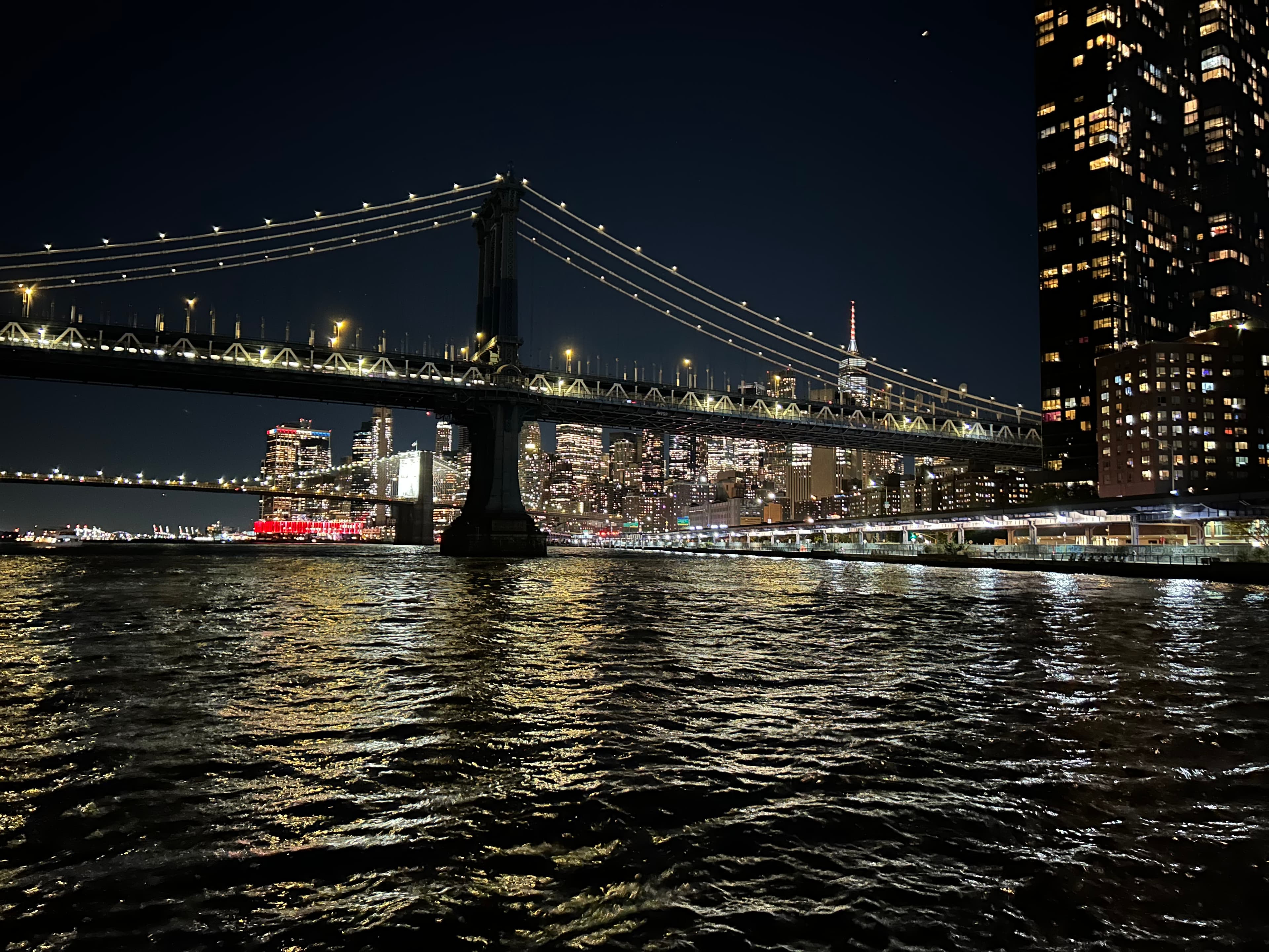 Manhattan Bridge lit up at night with the Lower Manhattan skyline behind it